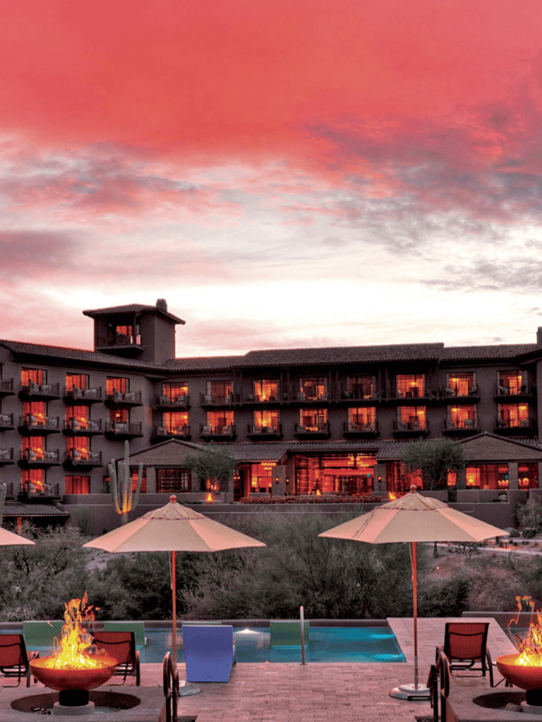 Luxurious hotel with pool and fire pits at sunset, perfect for relaxation and travel planning.