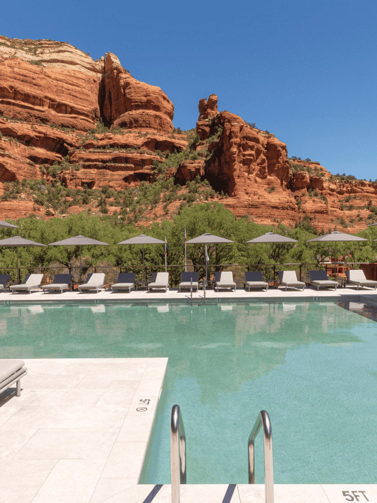 Secluded desert resort pool with canyon backdrop, outdoor lounge chairs, and scenic red rock mountains.