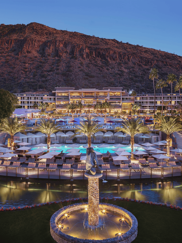 Luxurious beachfront resort at sunset with palm trees and mountain backdrop, perfect for travel and vacation planning.