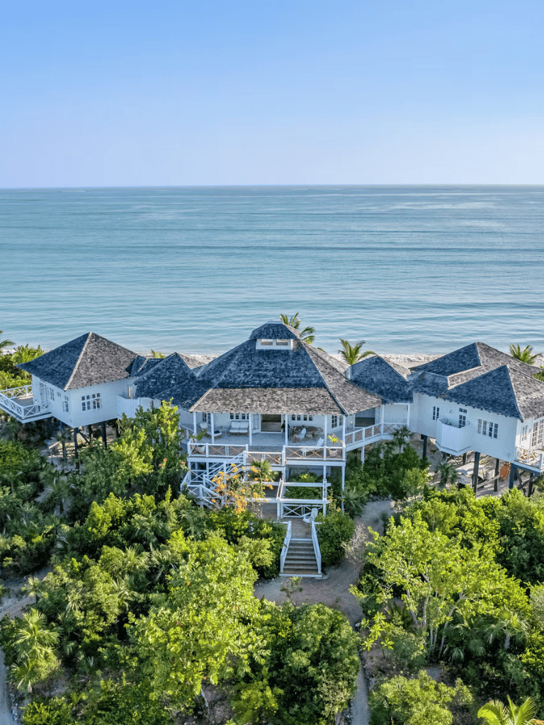 Luxurious beach house on tropical coastline with ocean view and lush greenery.