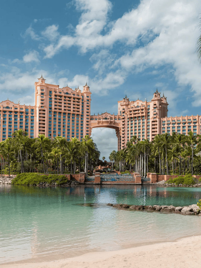 Luxurious pink hotel with tropical landscape and water view, perfect for vacation and travel planning.