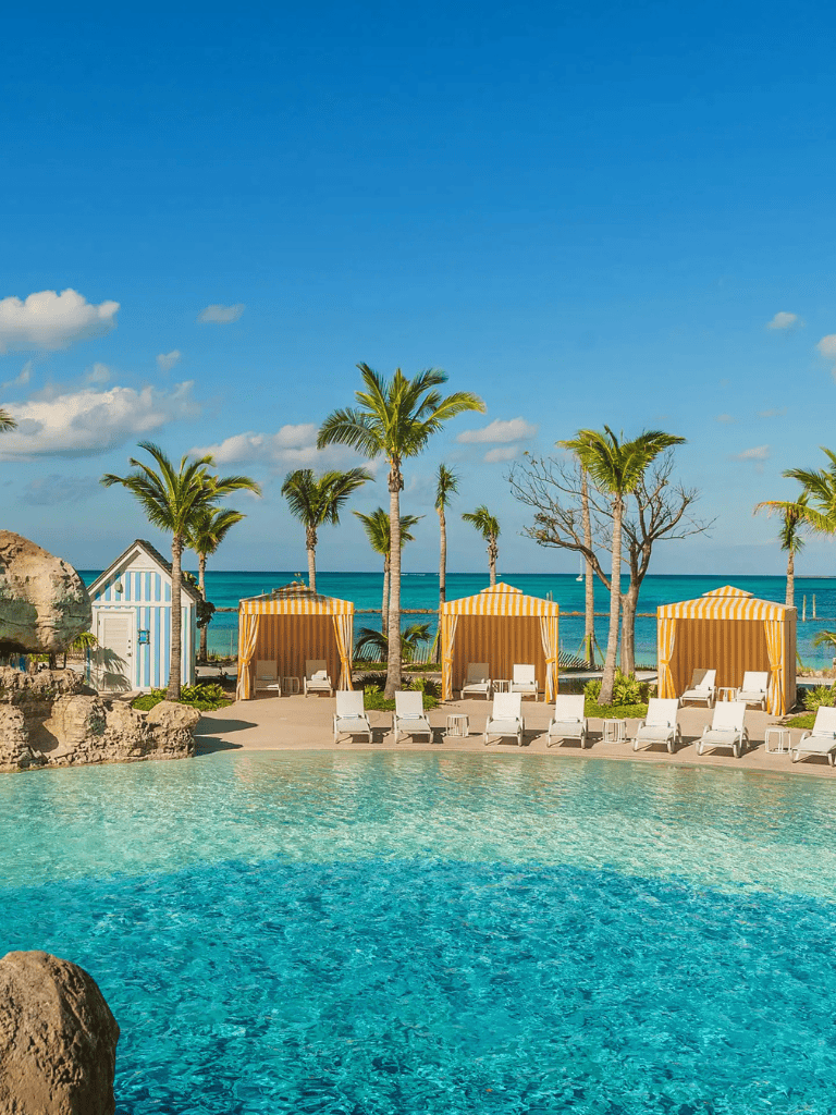 Relaxing poolside scene at a tropical beach resort with palm trees and cabanas.
