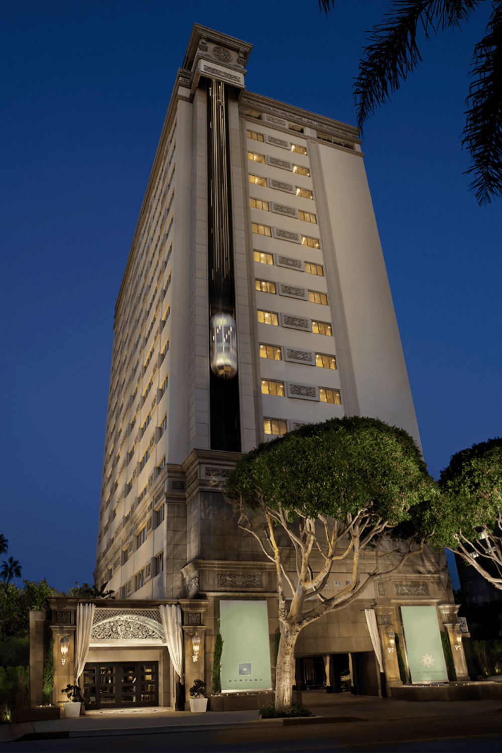Luxurious hotel building with elegant design, illuminated at dusk in downtown area.
