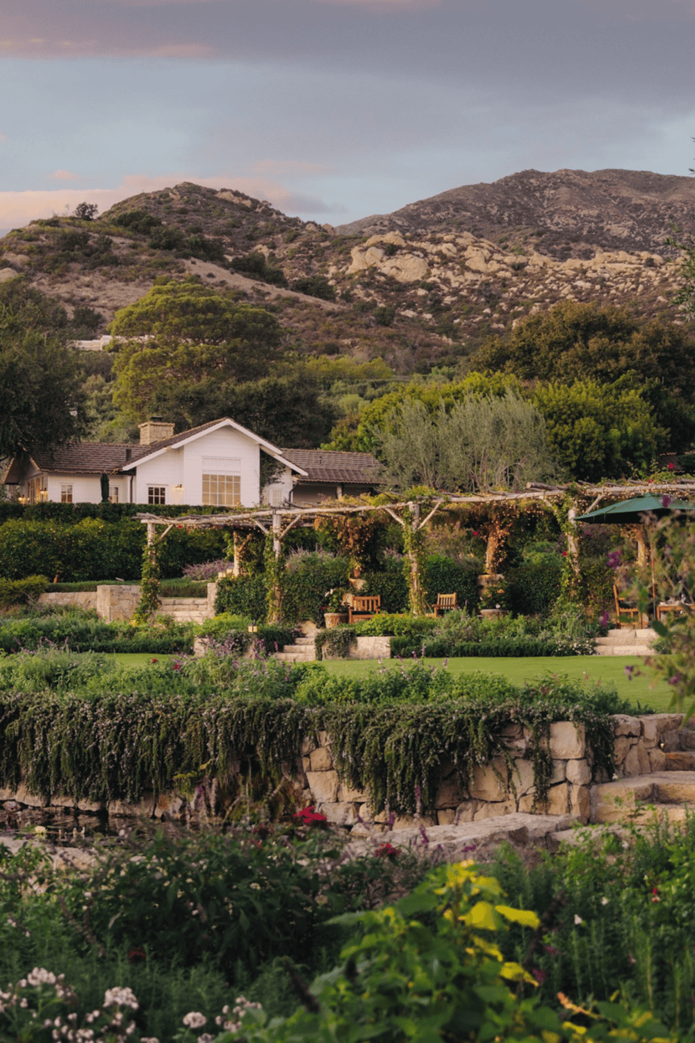 Serene garden landscape with mountains, greenery, and cozy white house, perfect for peaceful outdoor retreats.