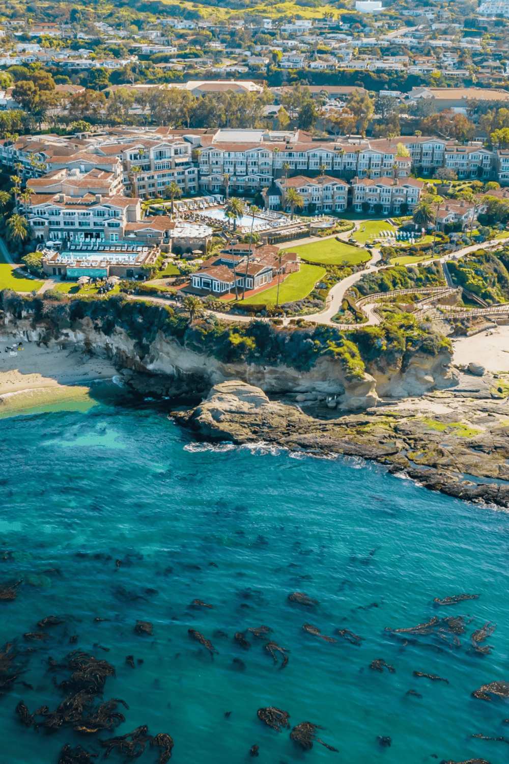 Clifftop luxury condos overlooking ocean with pools and landscaped gardens.