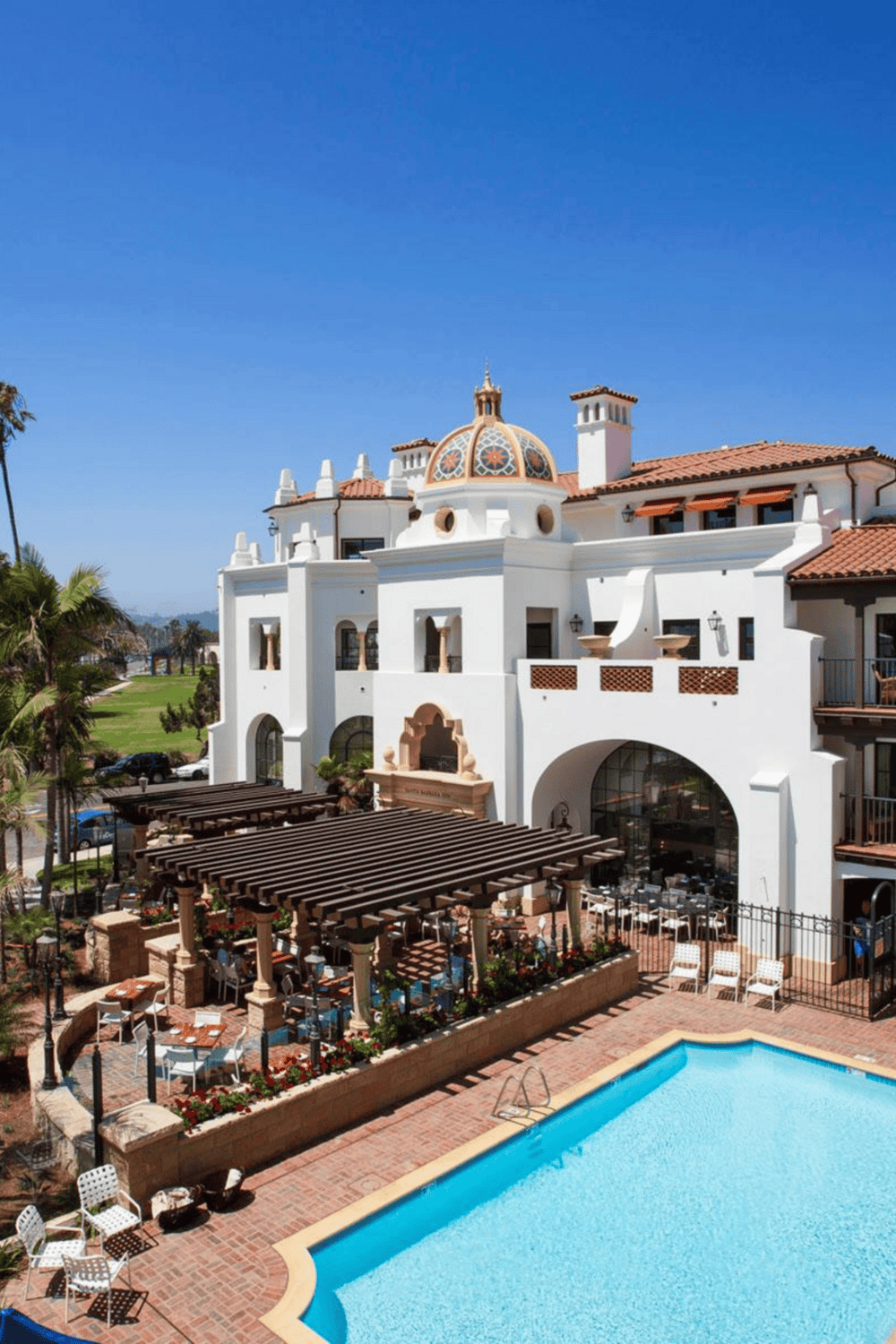 Elegant Spanish-style resort with pool, outdoor dining, and lush landscaping.
