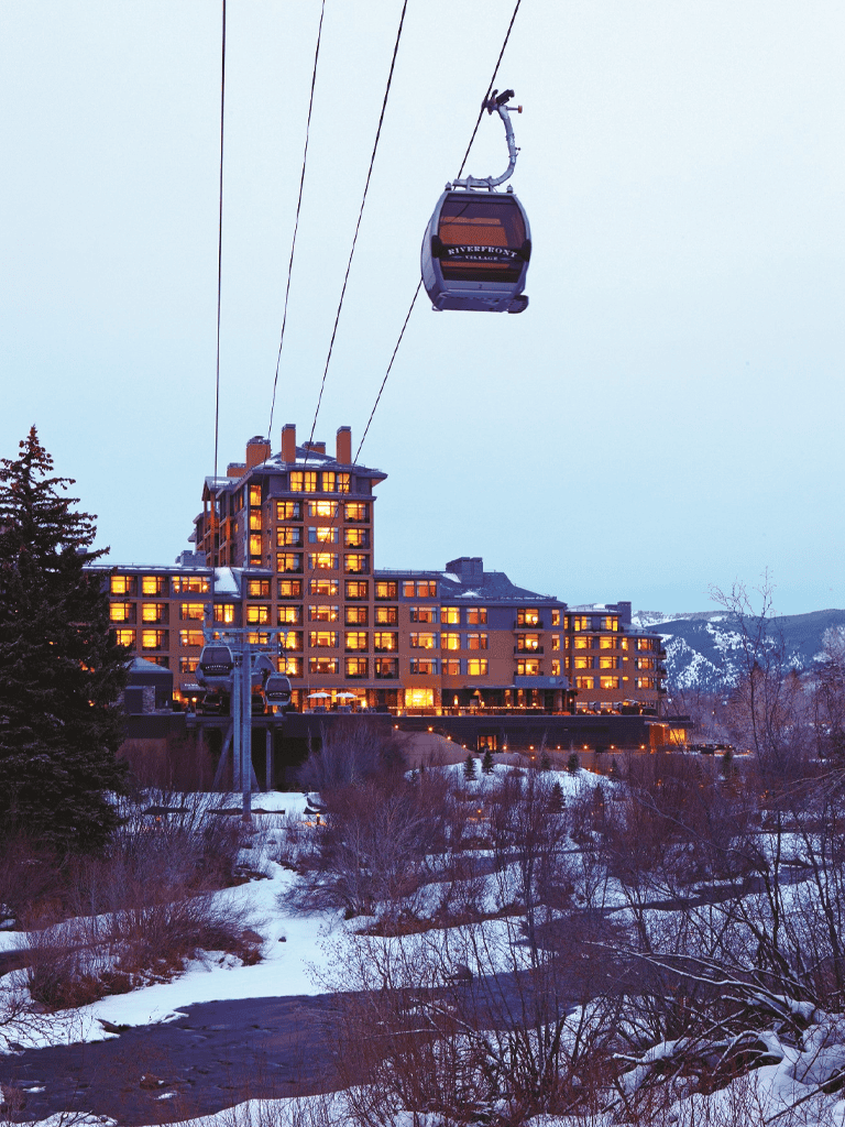 Beautiful mountain resort with gondolas, illuminated buildings, and snowy landscape for vacation planning.