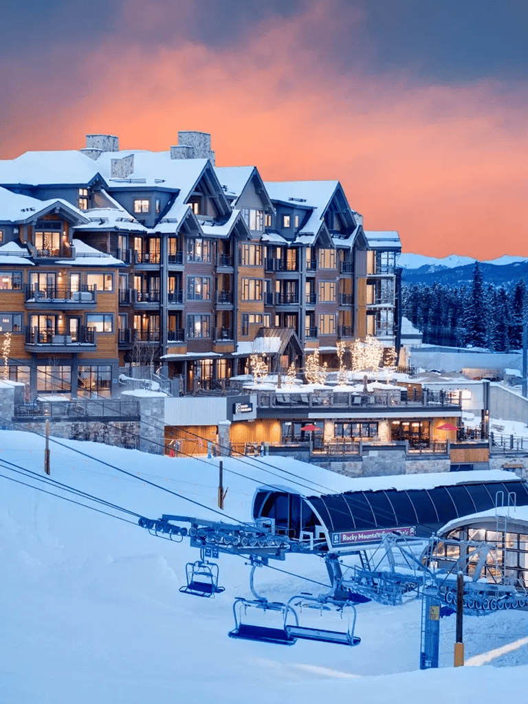 Snowy mountain resort with ski lifts and cozy lodge accommodations at dusk.
