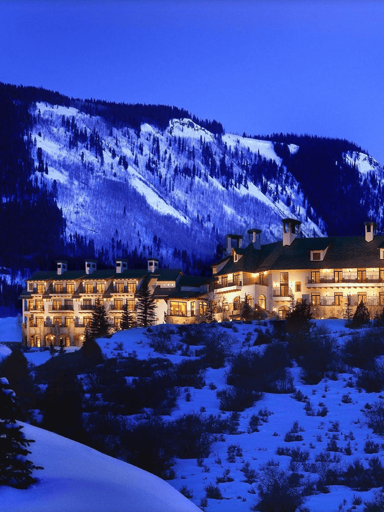 Snowy mountain hotel at night with illuminated windows and scenic winter landscape.