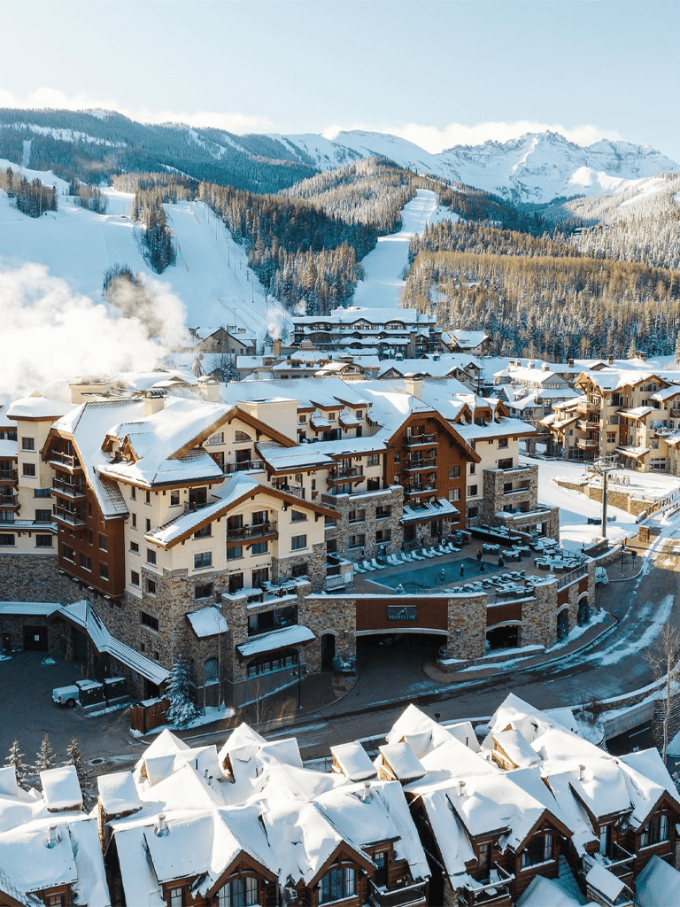 Snowy mountain resort with cozy chalets and ski slopes in the background.