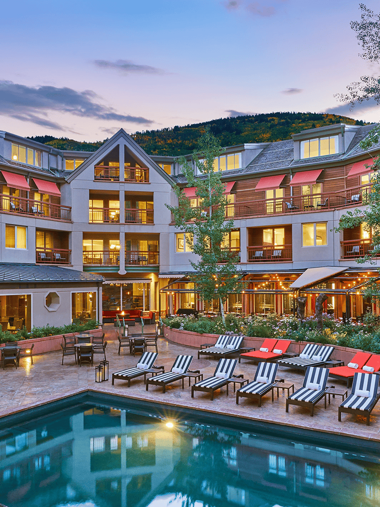 Luxurious hotel with outdoor pool and mountain views at sunset.