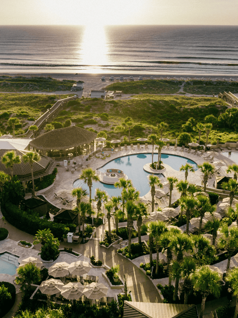 Beachfront ocean view with pool, lush greenery, and resort amenities.