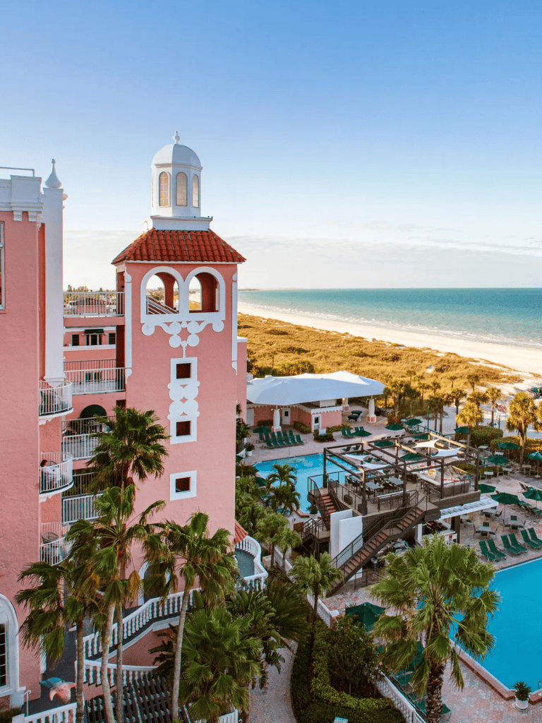 Stunning beachside hotel with pink architecture, pool, and ocean view for perfect vacation stays.