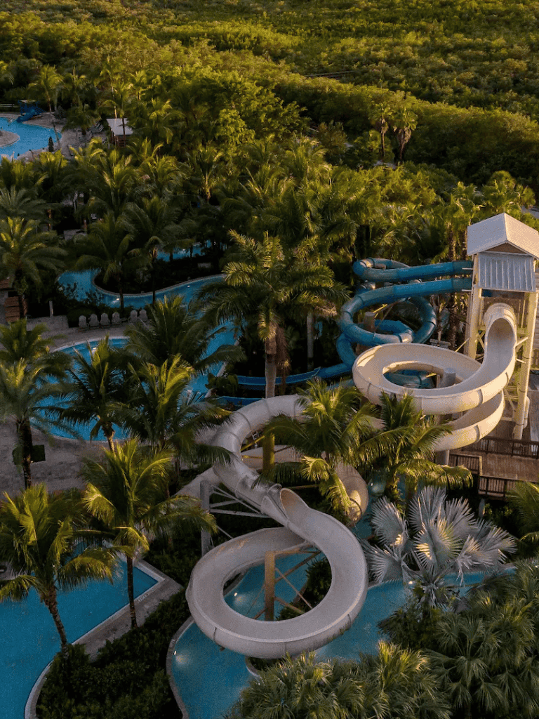 Thrilling water slides at Quest for Directions waterpark surrounded by lush palm trees and scenic greenery.