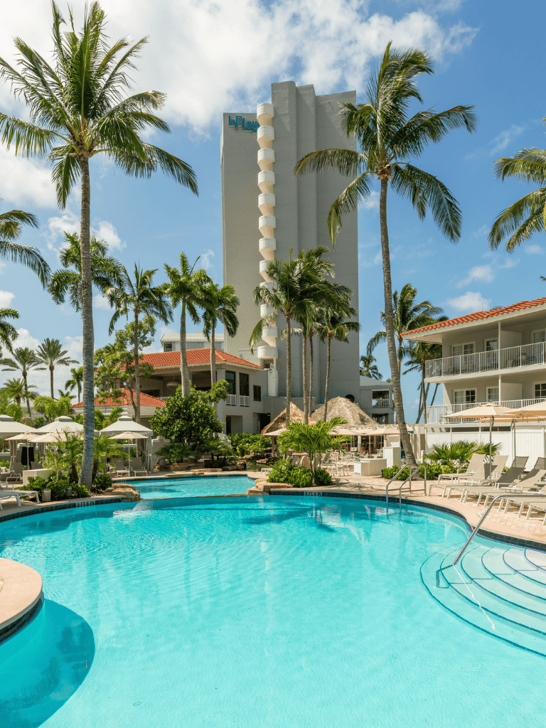 Luxury hotel pool with palm trees and ocean view in Miami.