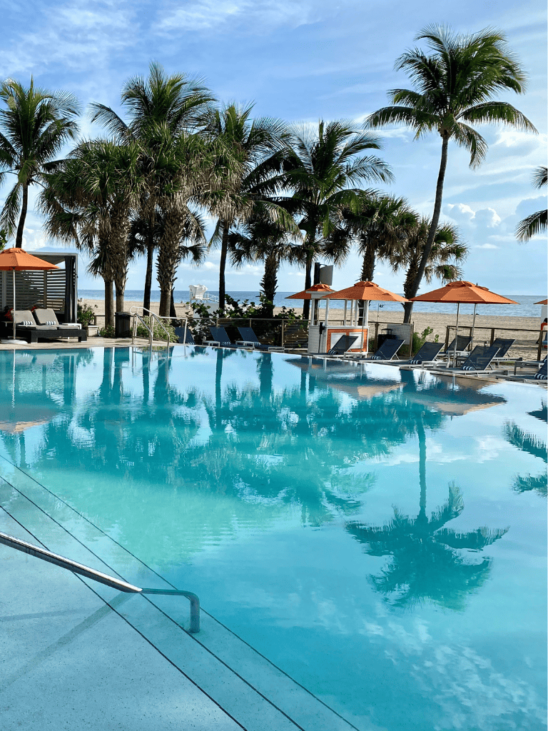Relaxing tropical beach with pool, palm trees, and ocean view at QuestForDirections resort.