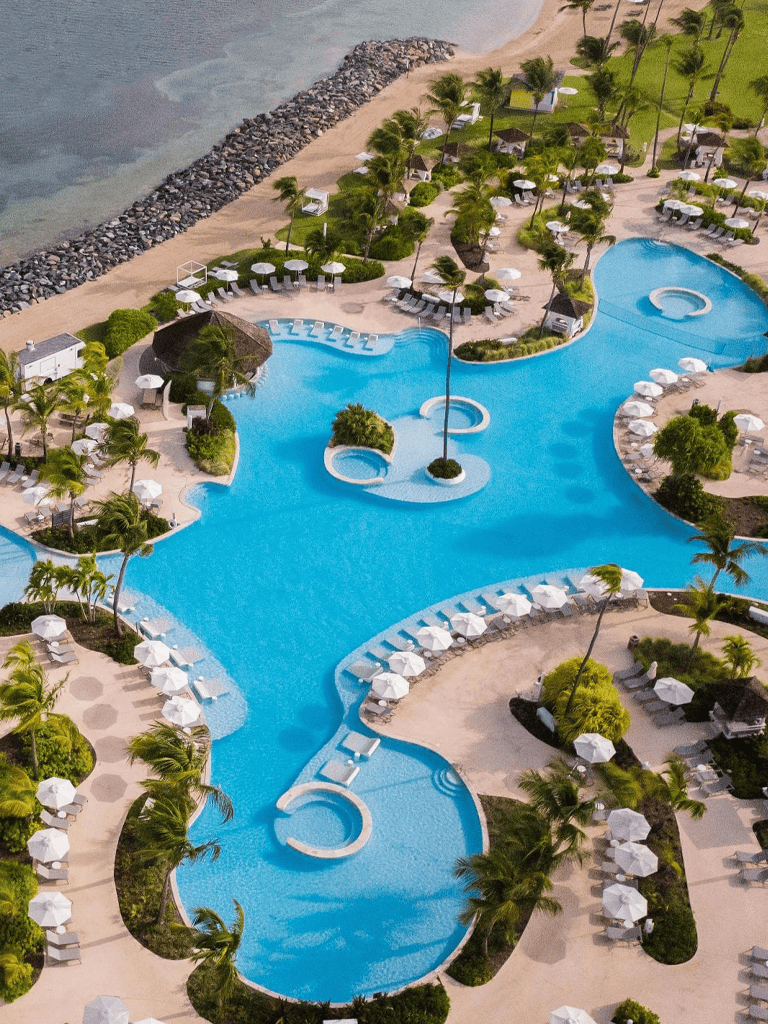 Luxurious hotel pool with tropical palm trees and beach access for vacation relaxation.