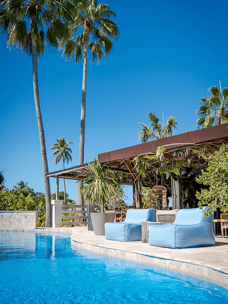 Relaxing poolside scene showcasing tropical palm trees and outdoor lounge chairs at a luxury resort.