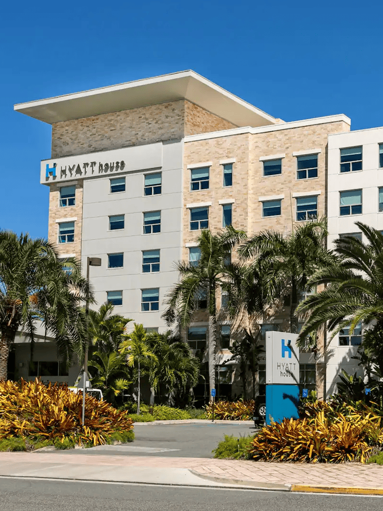 Luxury Hyatt House hotel in a tropical setting with palm trees and lush landscaping.