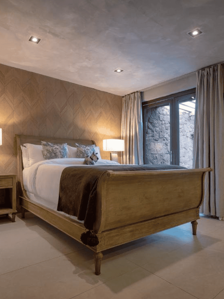 Luxurious hotel bedroom with wooden bed frame, soft bedding, and elegant lighting for a restful stay.