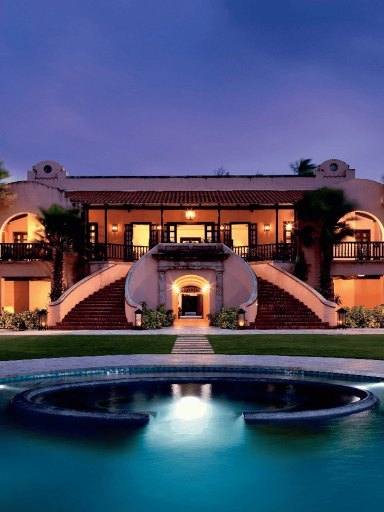 Luxury Mediterranean-style villa with courtyard and swimming pool at dusk.
