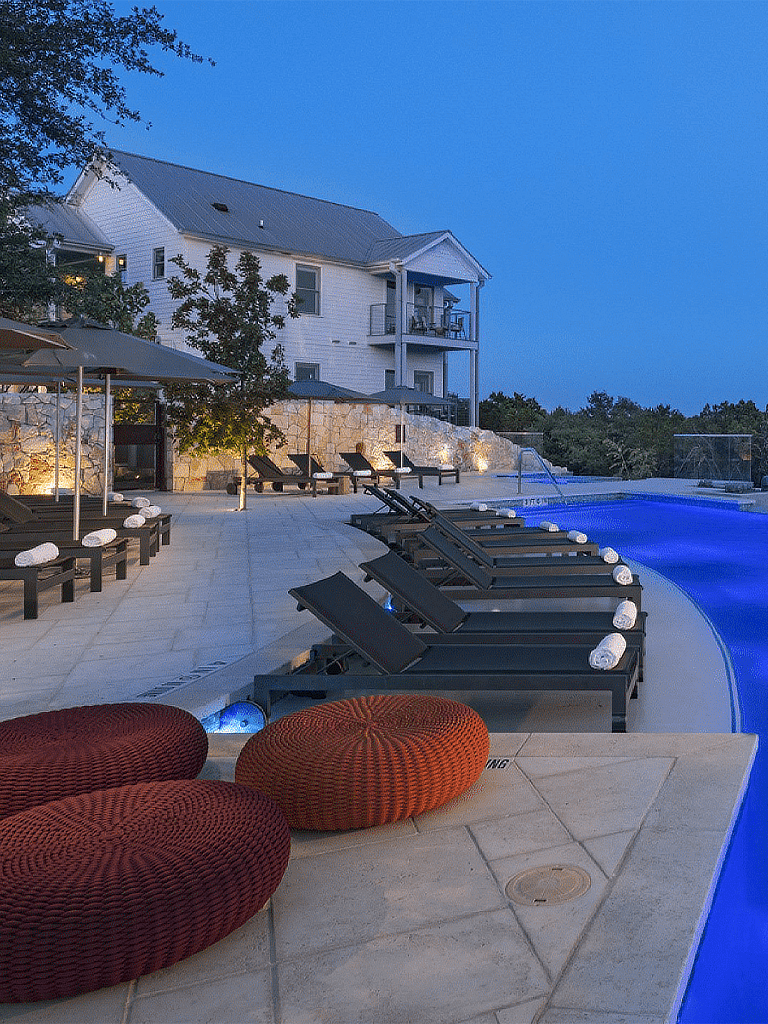 Luxury hotel swimming pool with lounge chairs and beautiful architecture.