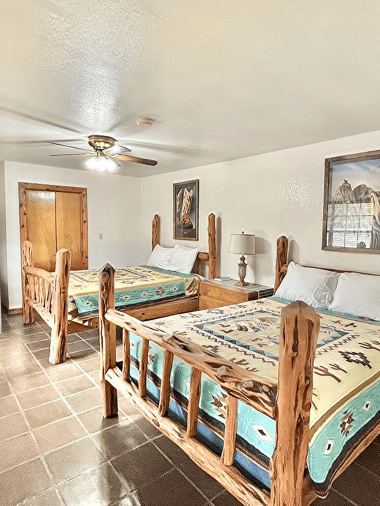 Cozy rustic bedroom with wooden log beds, Western decor, and southwestern artwork, perfect for authentic travel stays.