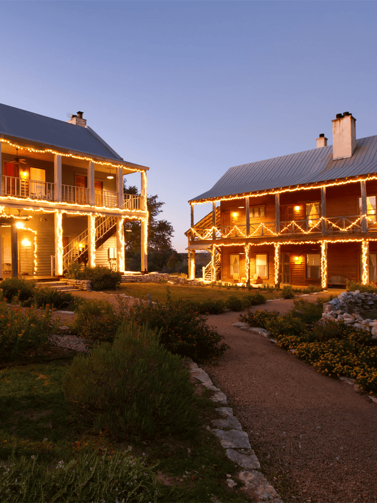 Charming rustic cottages decorated with warm string lights at dusk, ideal for cozy retreats.
