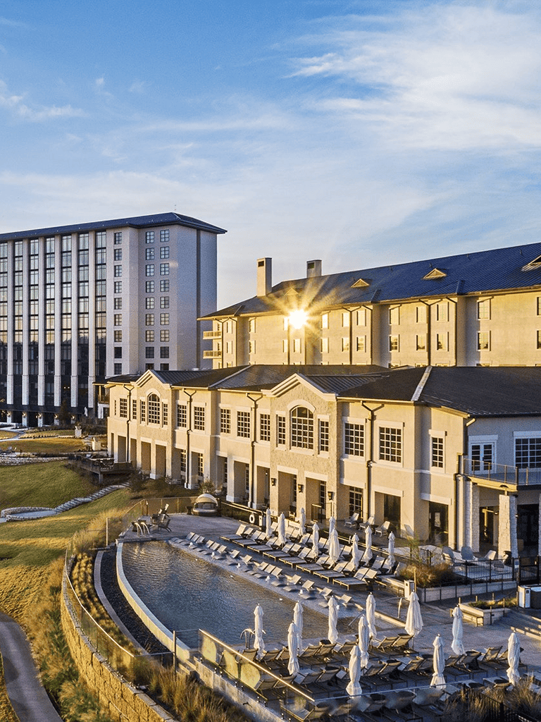 Modern hotel with outdoor pool, sun loungers, and urban skyline.