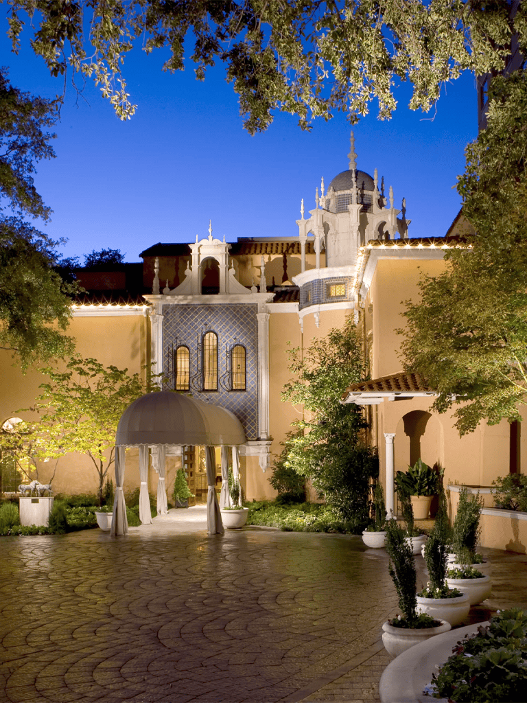 Elegant Indian palace exterior at dusk, beautifully lit with ornate architecture and lush landscaping.