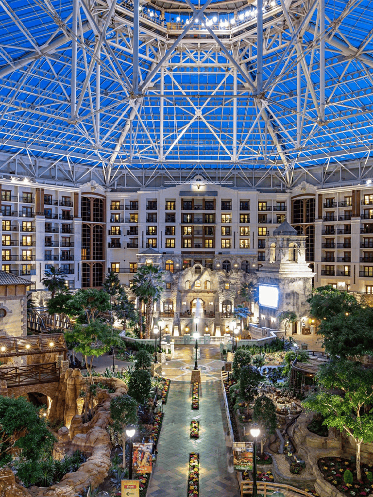 Indoor hotel atrium with glass ceiling, lush greenery, and intricate architecture in Las Vegas.