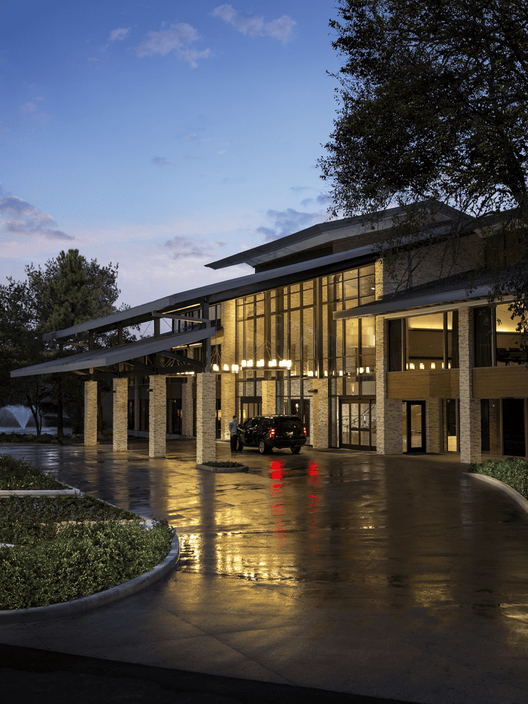 Contemporary modern building exterior with illuminated entrance at dusk, professionally lit architecture.