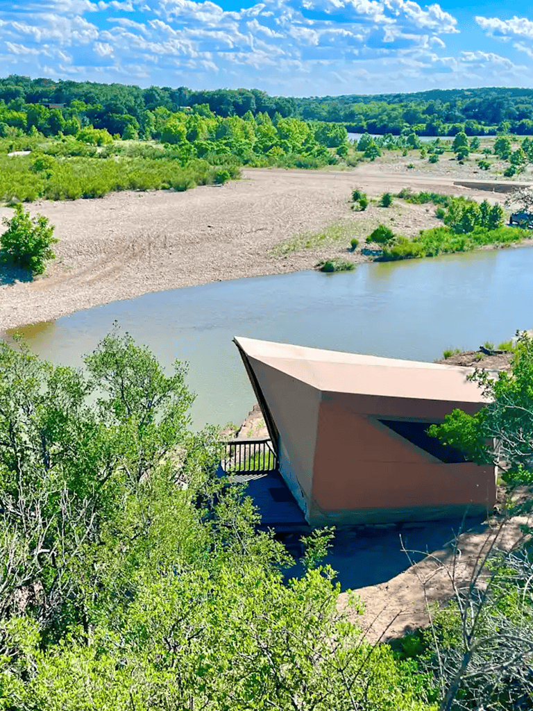 Vibrant river and lush greenery with modern architectural structure in scenic outdoor setting.