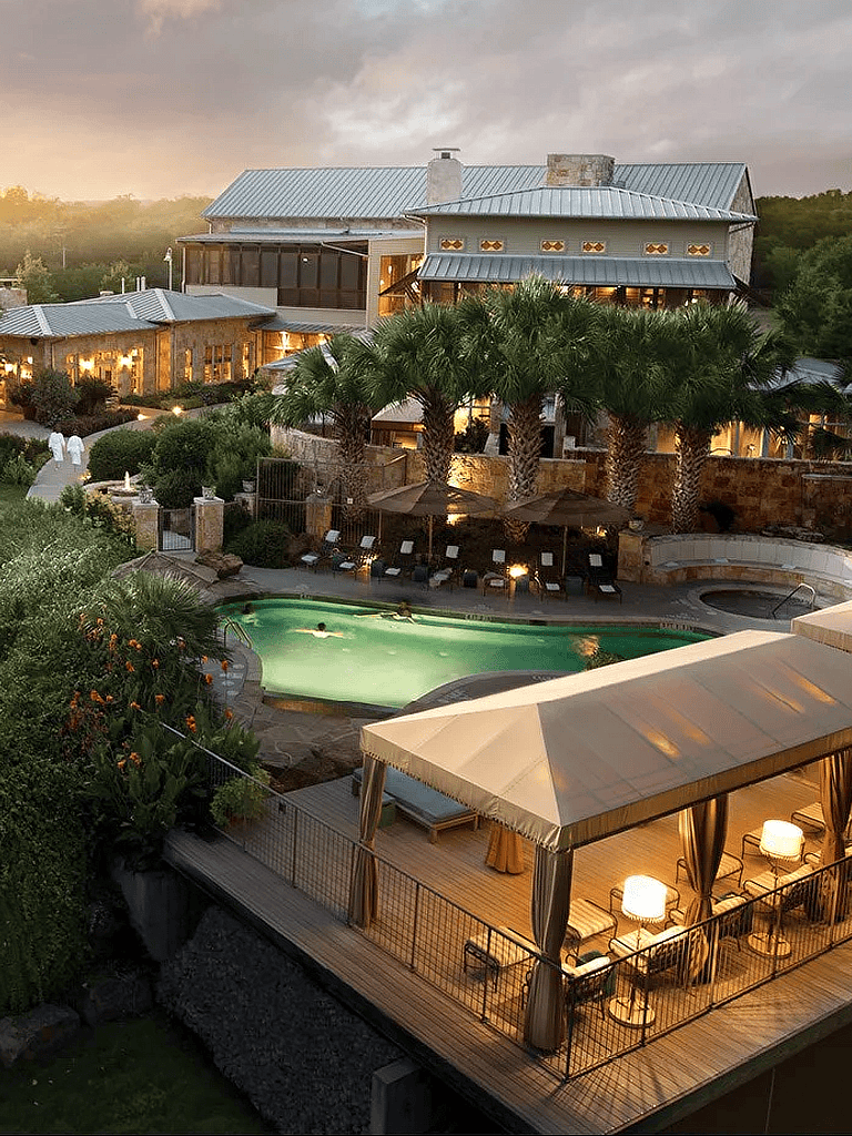 Luxurious vacation villa with pool, lush greenery, and elegant outdoor seating at sunset.