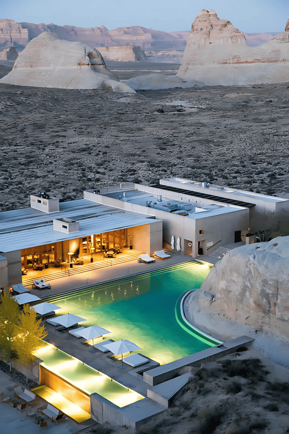 Luxury desert resort with infinity pool overlooking rocky landscape and dramatic cliffs.
