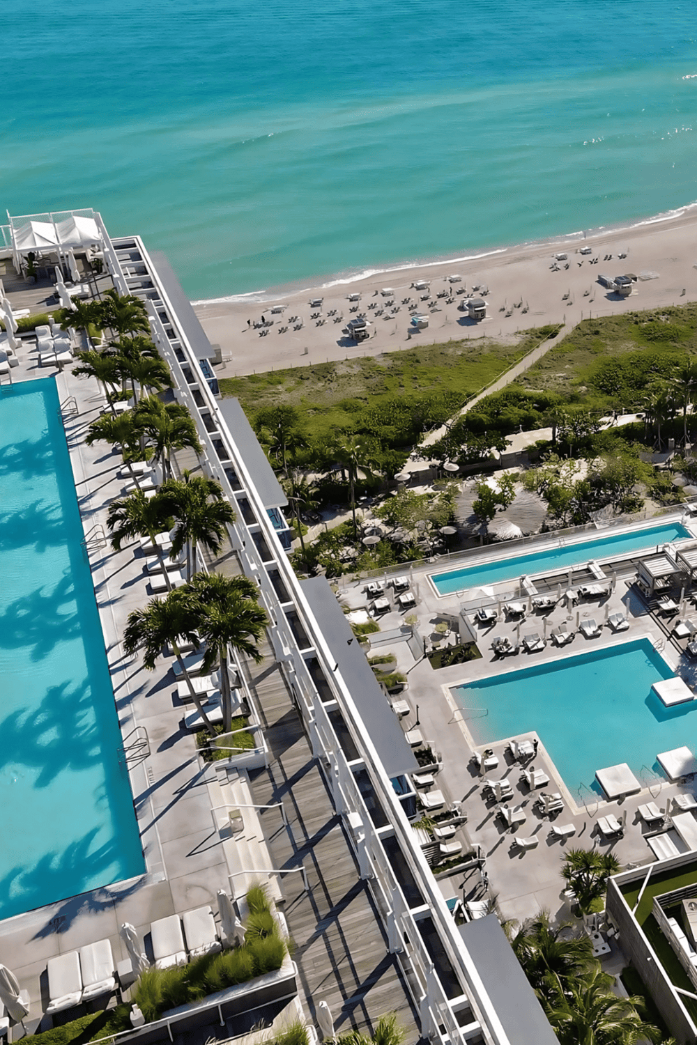Aerial view of luxury beachfront hotel with swimming pools and ocean access, ideal for vacation relaxations.