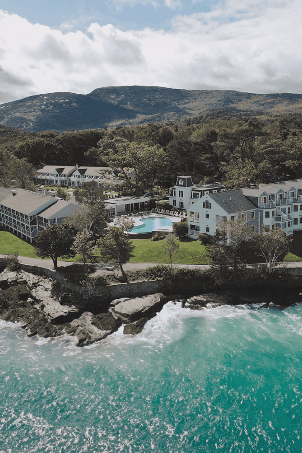 Luxurious beachfront resort with ocean view, pool, and mountain backdrop for relaxing vacation.