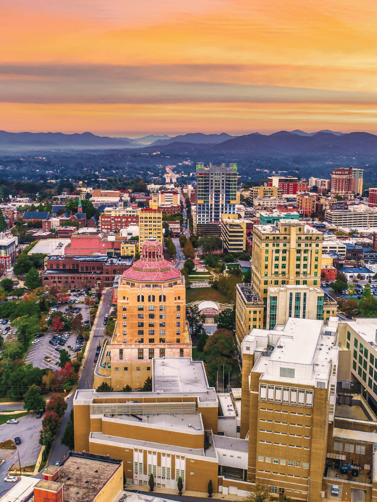 Vibrant cityscape of QuestForDirections with downtown buildings and mountainous backdrop at sunset.