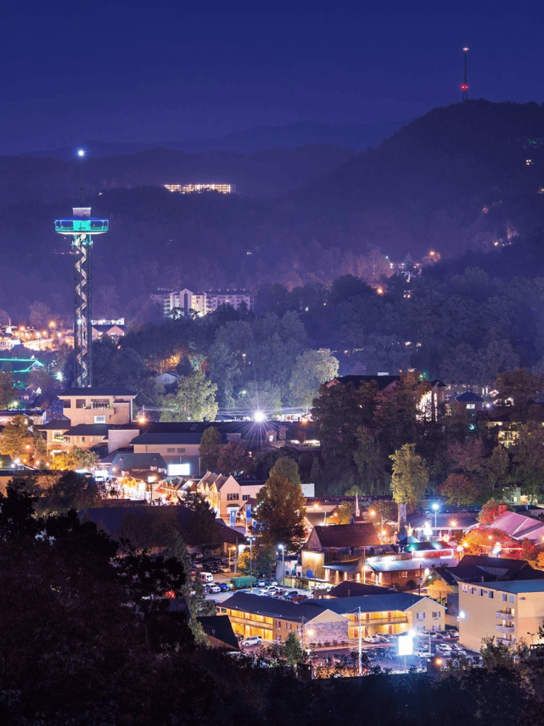 Bright mountain town at night with city lights and communication towers, vibrant and scenic environment.
