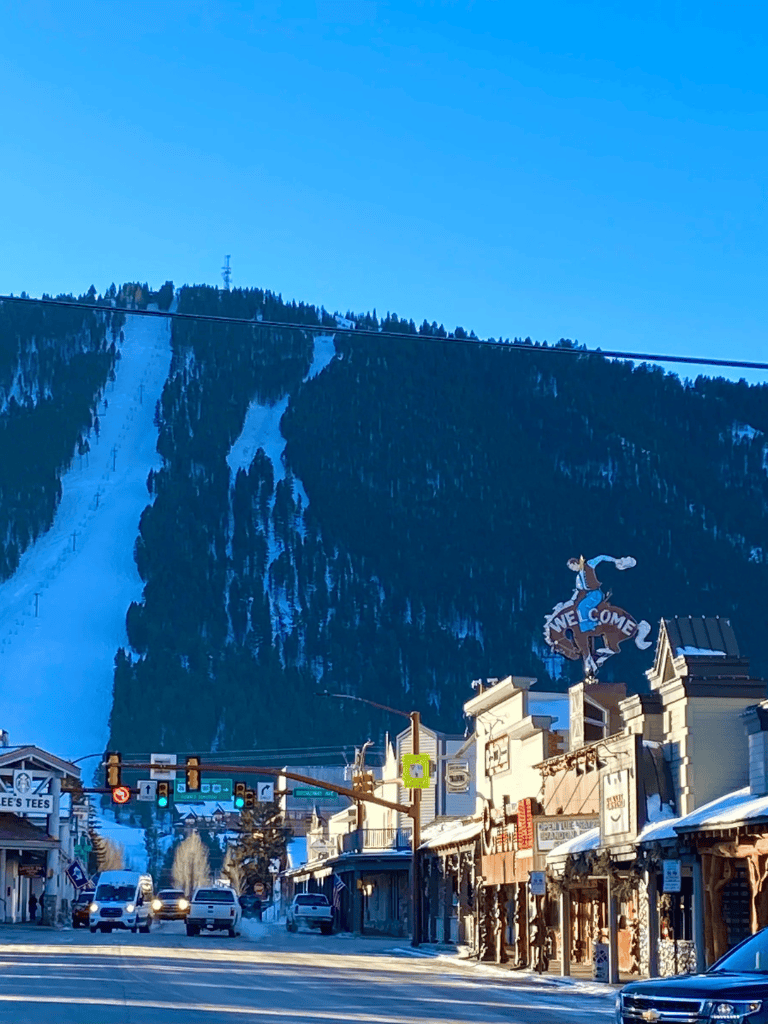 Snowy mountain scenery with a bustling town street in the foreground, ideal for outdoor adventure and travel destinations.