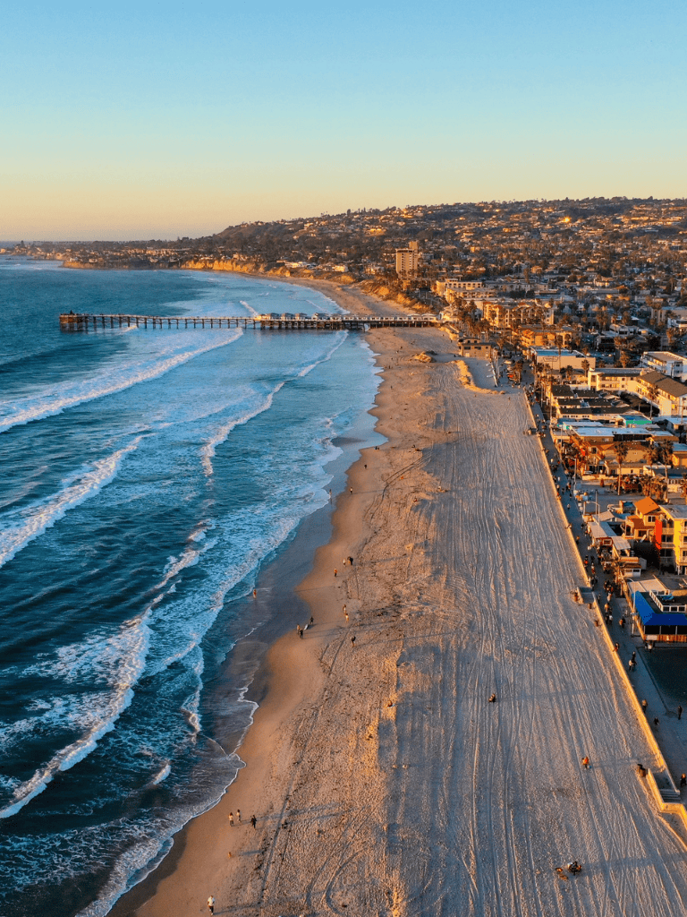 Sweeping view of the California coast at sunset, highlighting nearby city and beach scene for travel and navigation inspiration.
