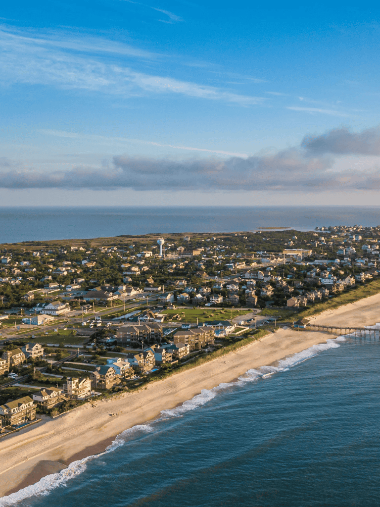 Aerial view of coastal town with beach, ocean, and residential area in daytime.