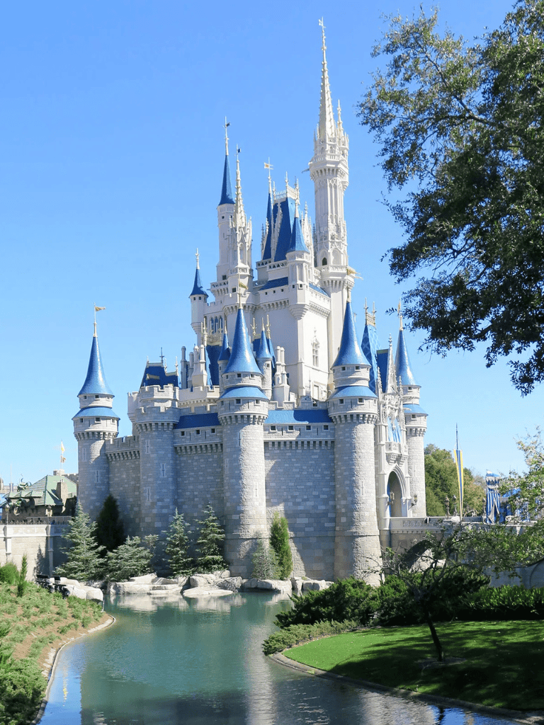 Fairy-tale castle at Disney theme park with blue turrets and stone walls on a sunny day.