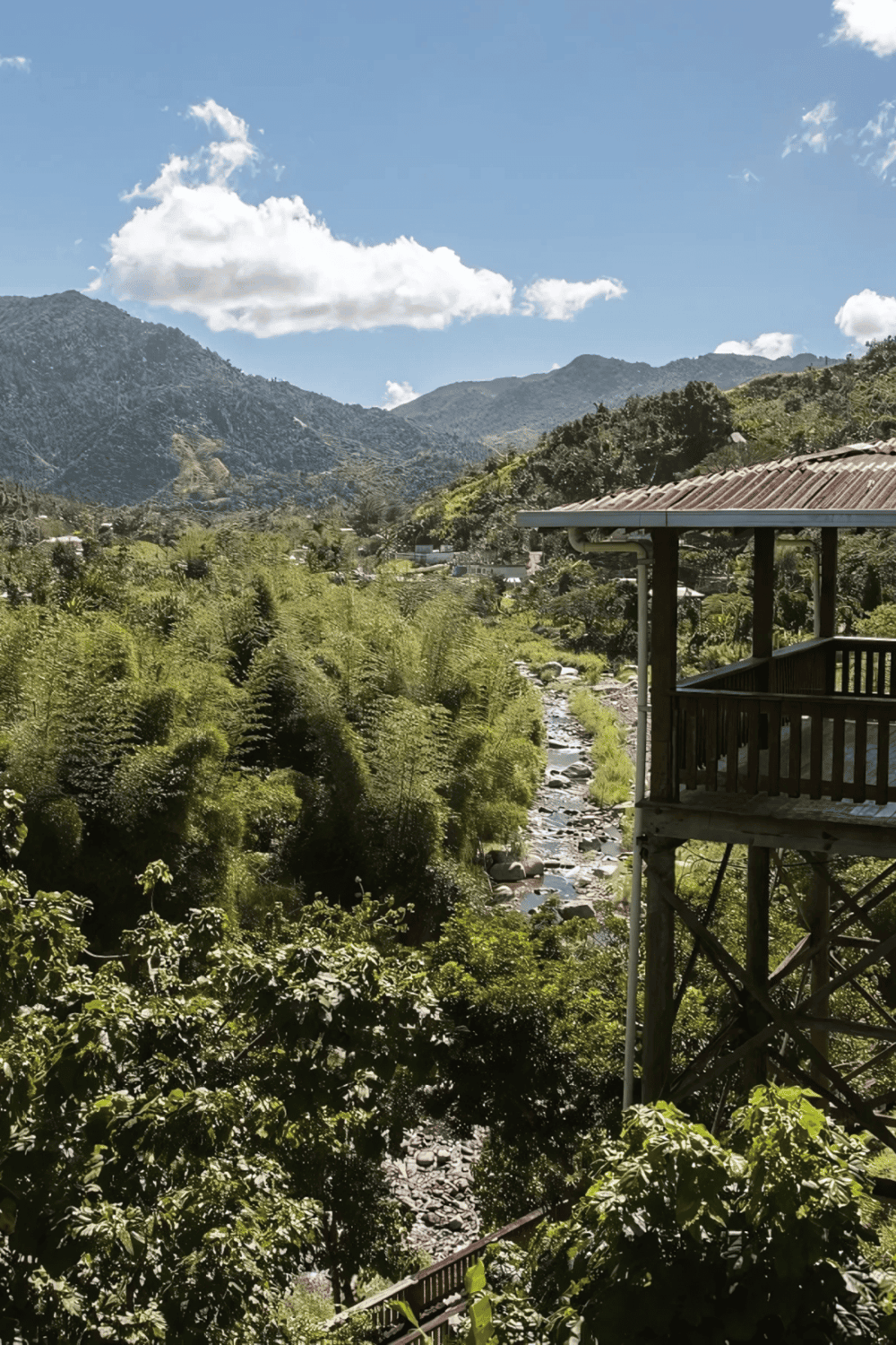 Serene mountain landscape with lush greenery, river, and wooden balcony for outdoor relaxation.