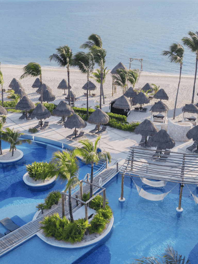 Relaxing beachfront resort with pool, tropical palm trees, and shaded hammock areas.