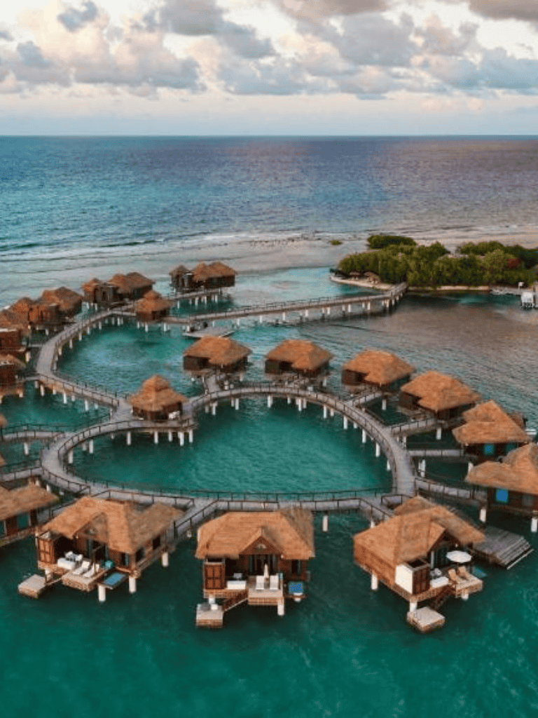Overwater Bungalows at a tropical beach resort with infinity pools and lush greenery.
