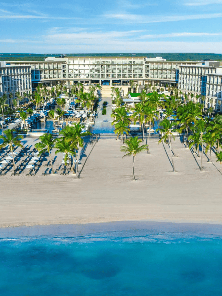 Luxurious beachfront hotel with palm trees and pool, perfect for vacation relaxation.