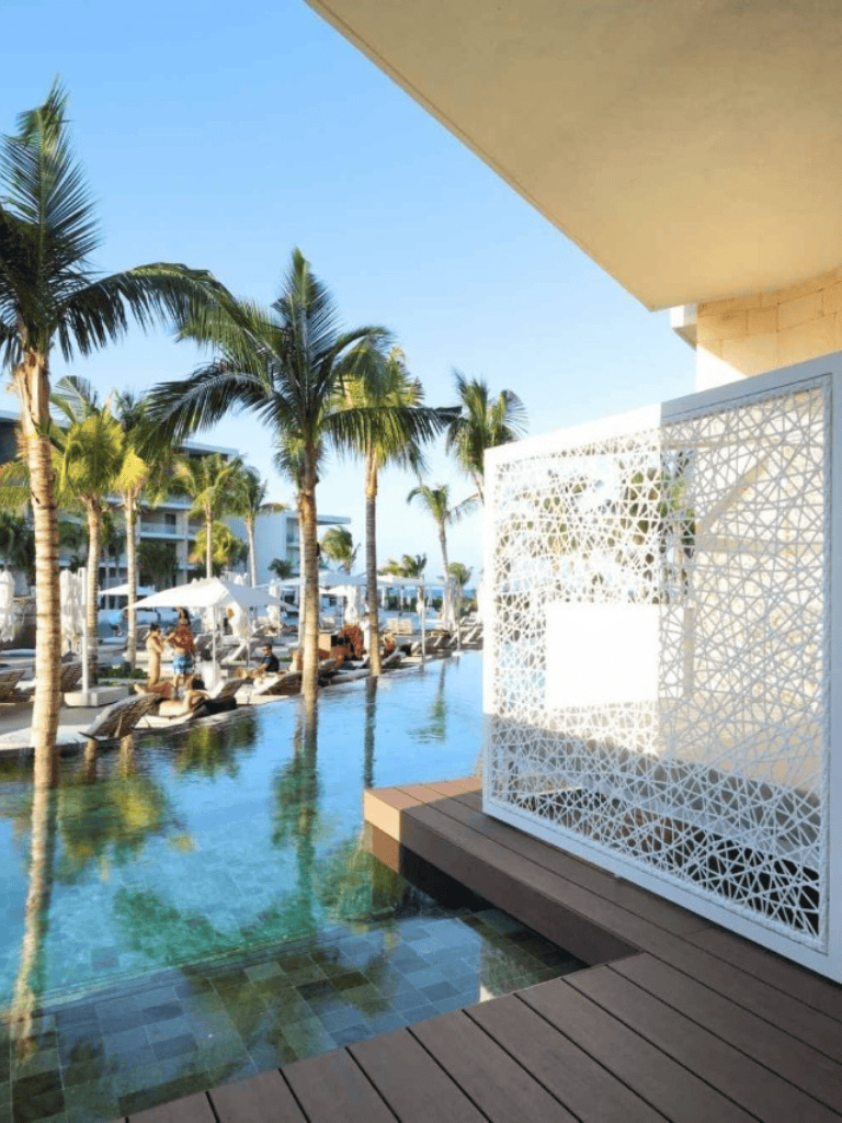 Luxurious poolside resort with palm trees and modern outdoor lounge area in tropical getaway.