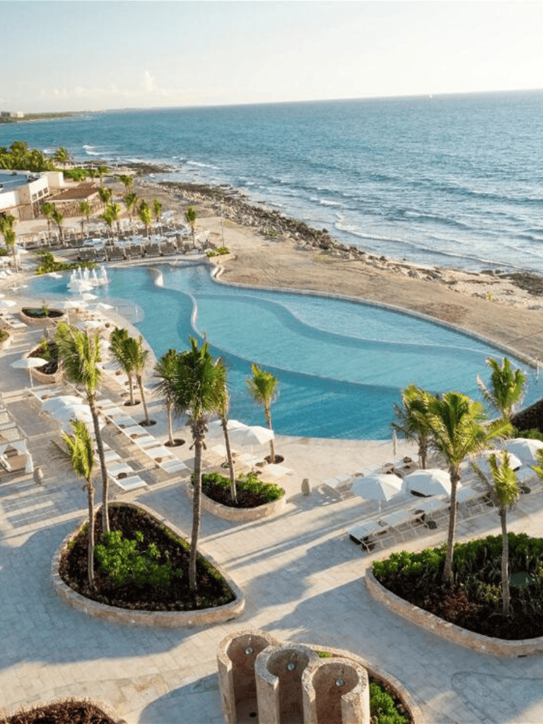 Relaxing poolside view at a beachfront resort with ocean access and palm trees in sunny tropical destination.