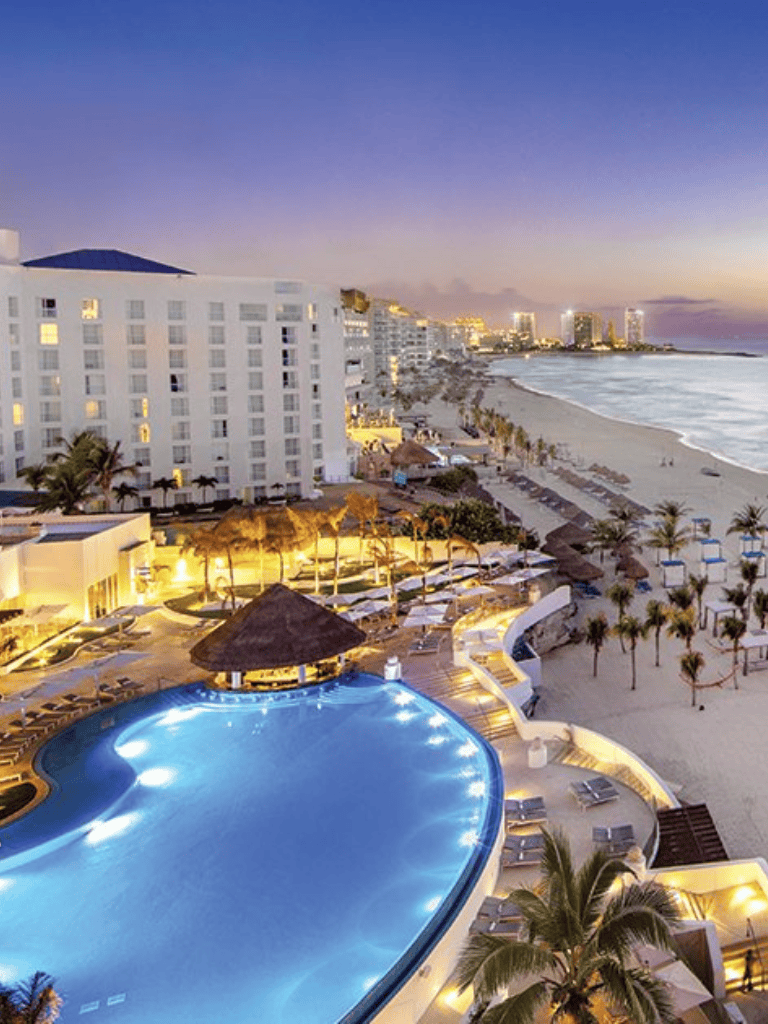 Luxurious beach resort with pool and ocean view at sunset in Cancun, Mexico.